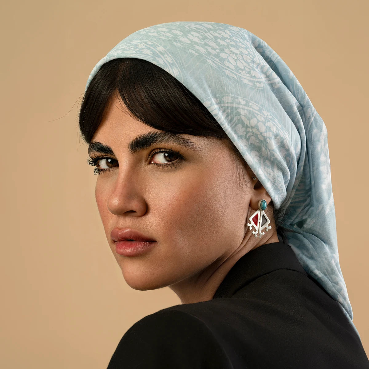 model wearing handmade triangular silver and enamel earrings decorated with Persian turquoise