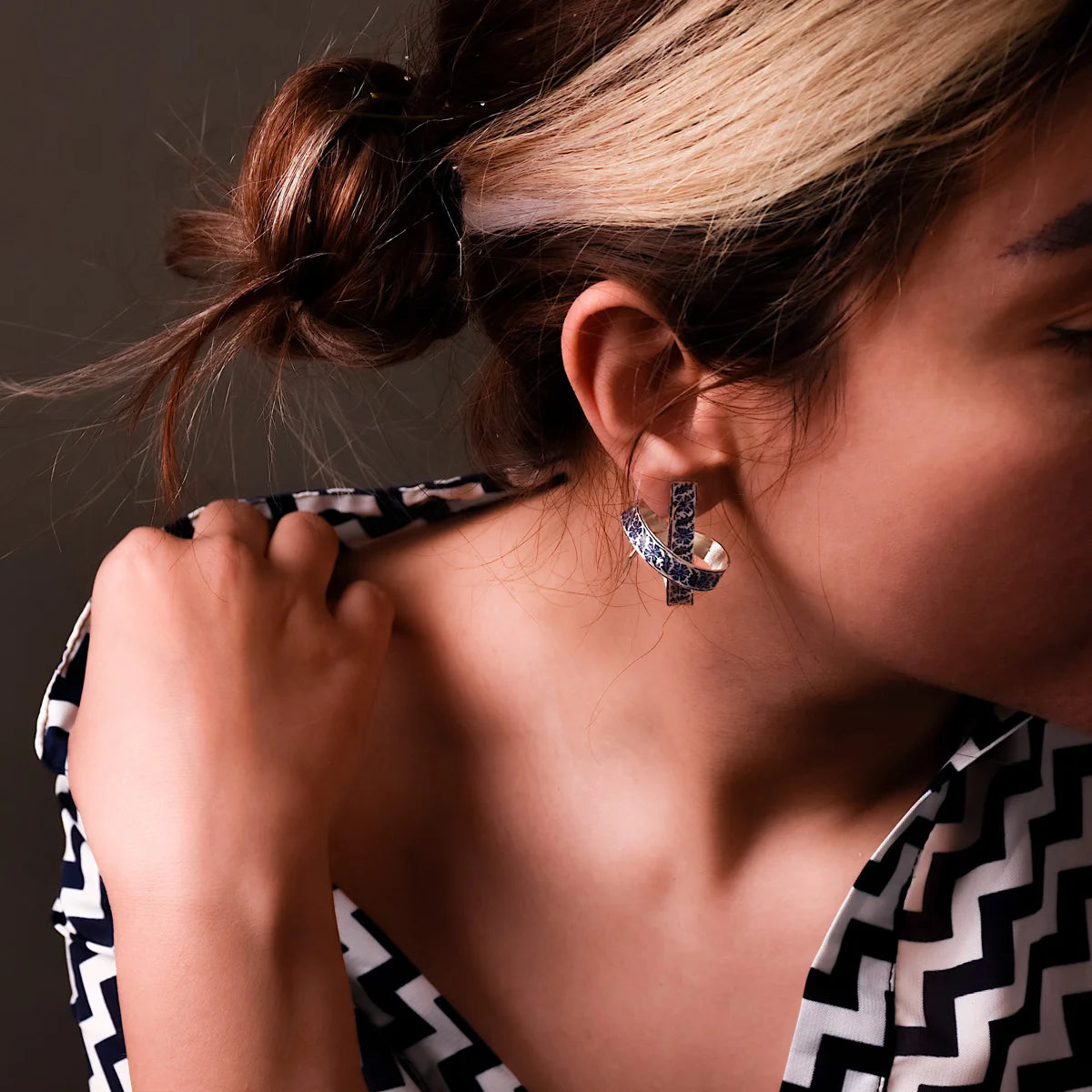 woman wearing unusual handmade silver earrings with blue black floral patterns
