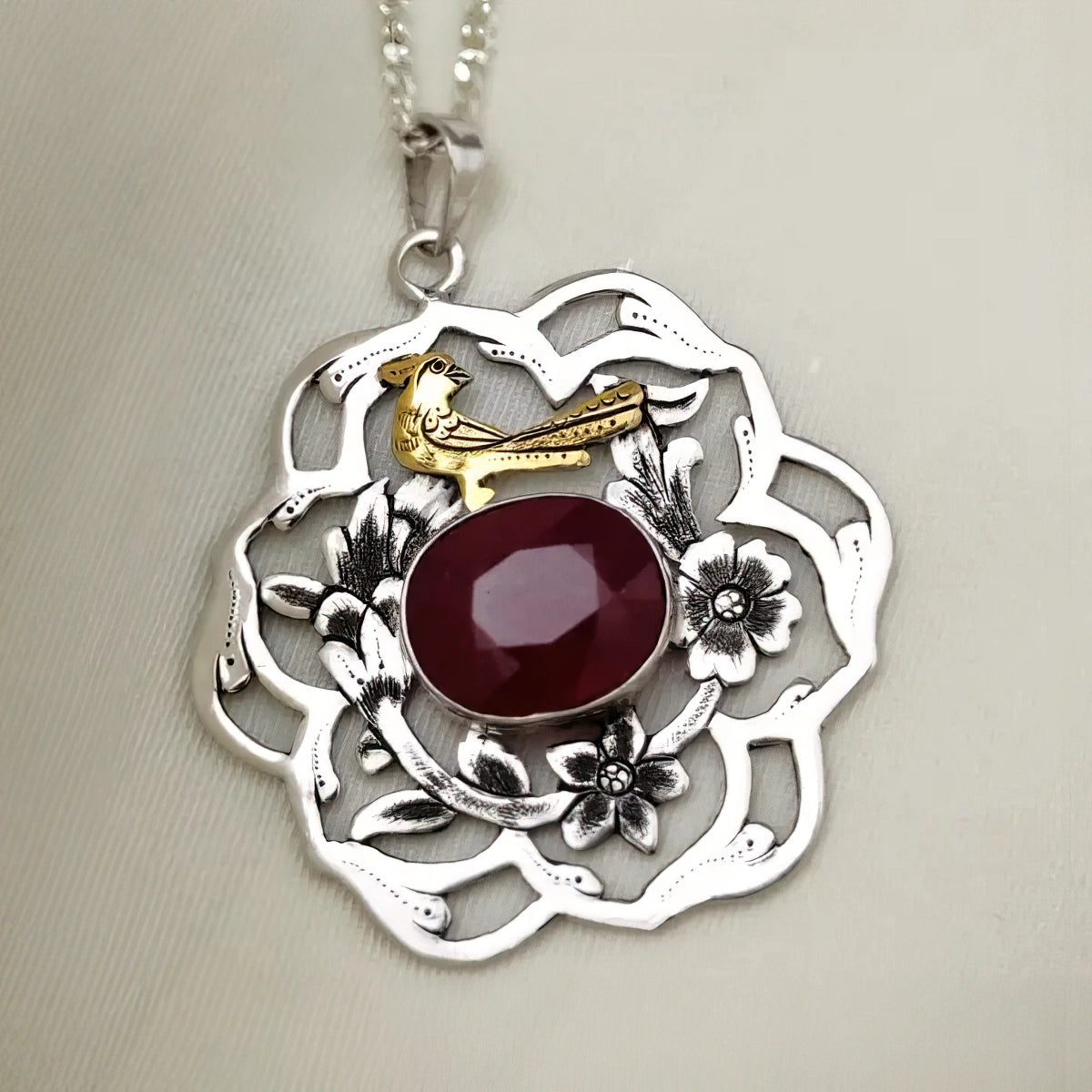 Hand-engraved openwork silver outer flower with a gold-plated bird and smaller flowers and ruby