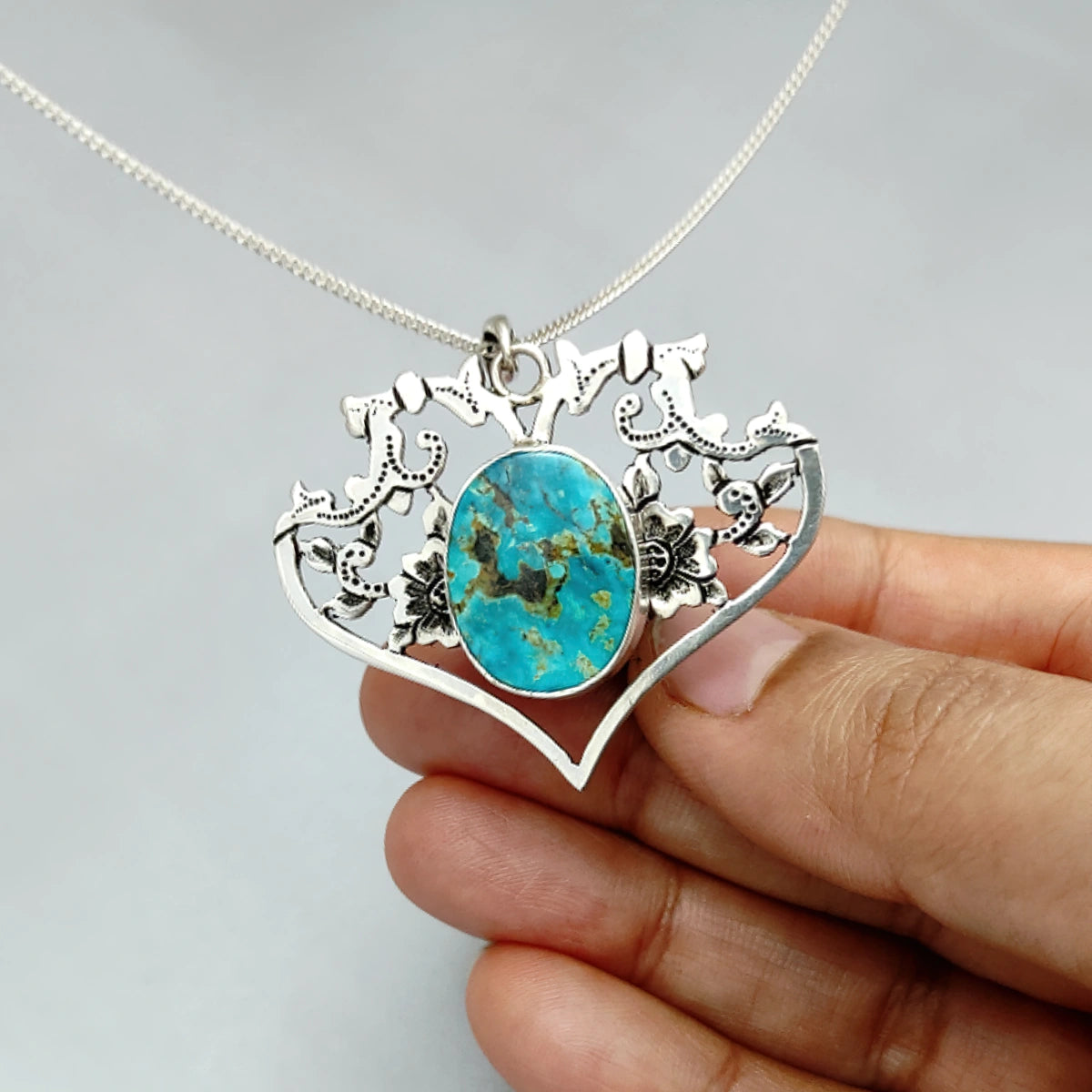 hand-engraved openwork floral patterns shaping a heart pendant necklace with Persian turquoise