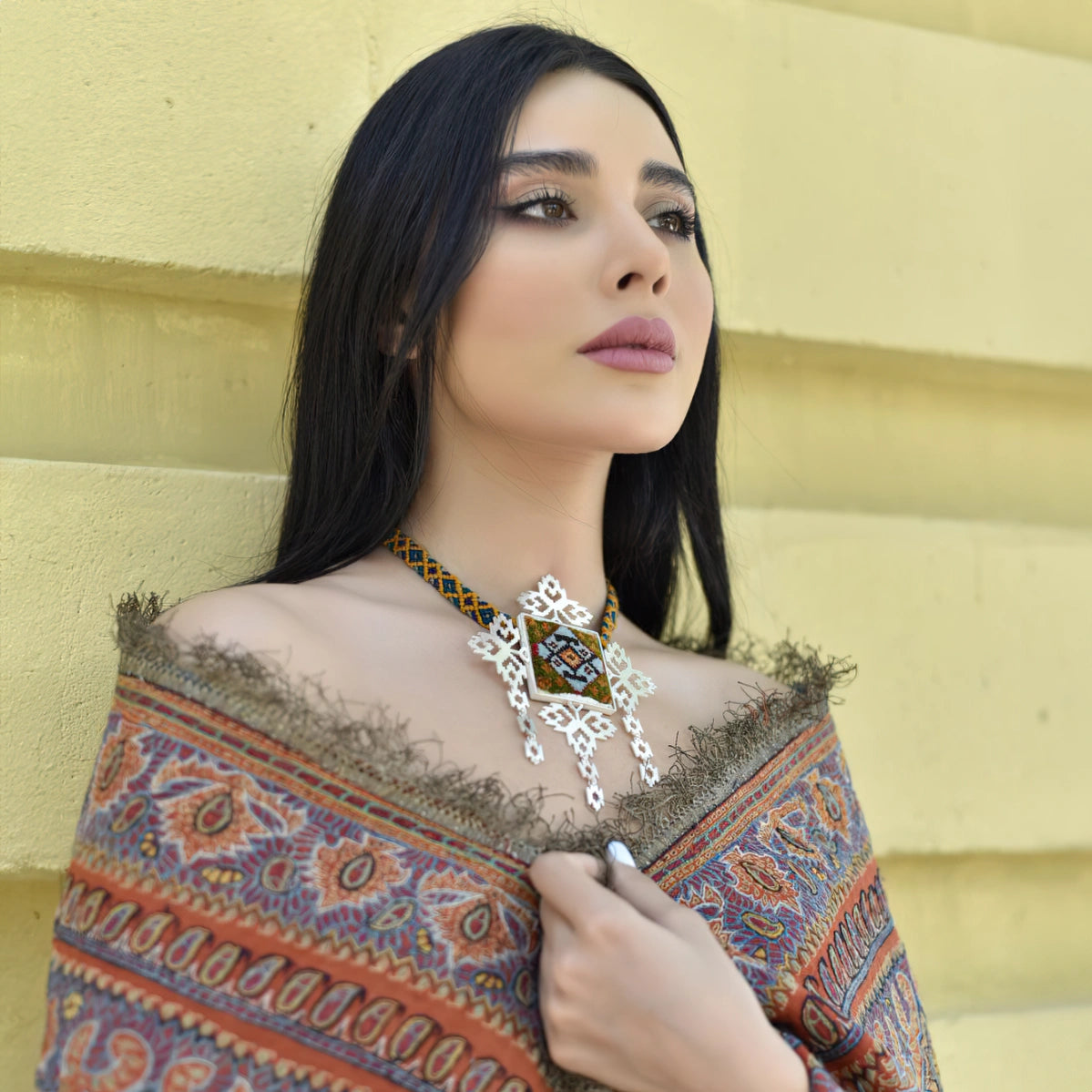 model wearing handmade openwork silver statement necklace with green, orange and blue colored Persian rug decoration
