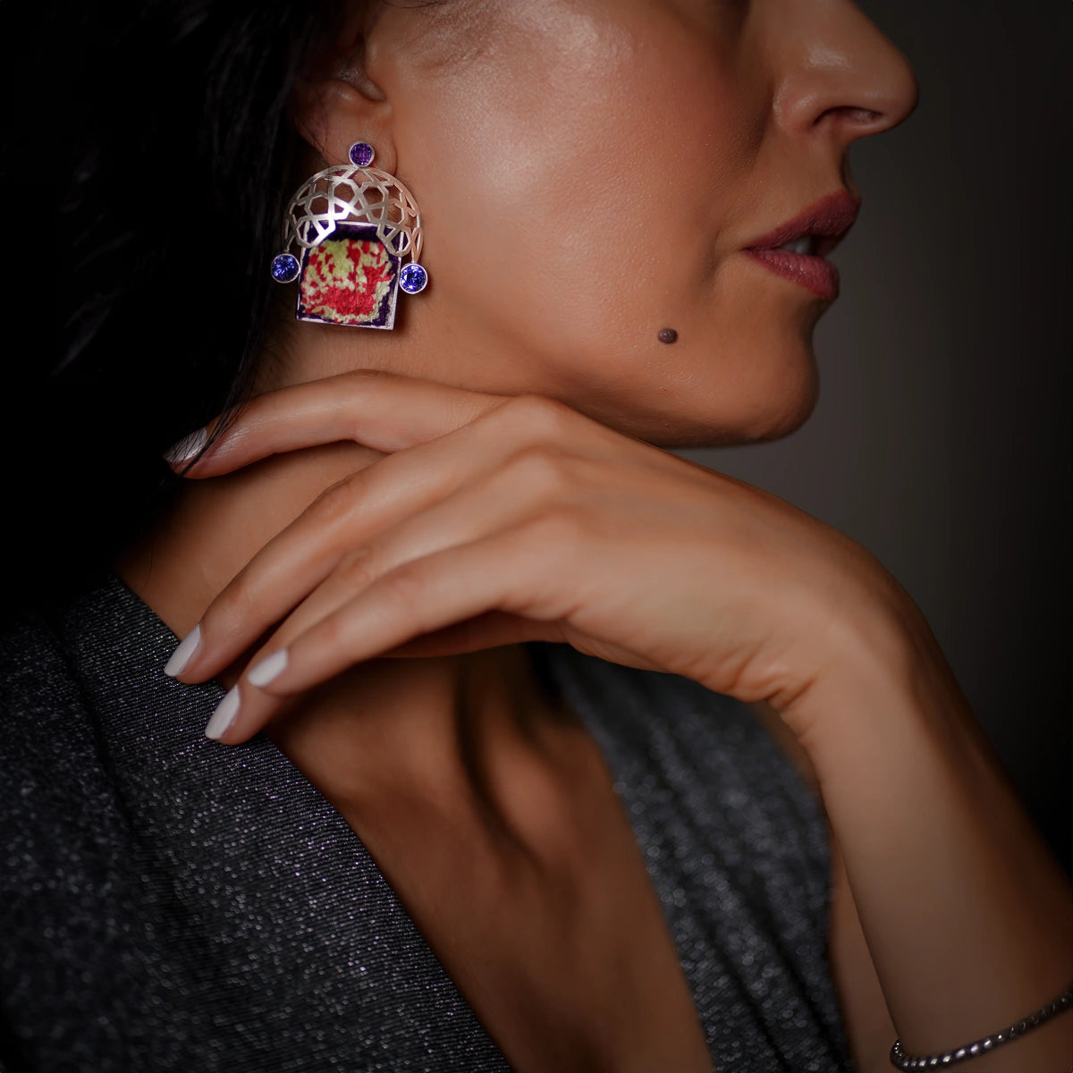 model wearing handmade 3D silver statement earrings with silk Persian rug and silver openwork silver decorations