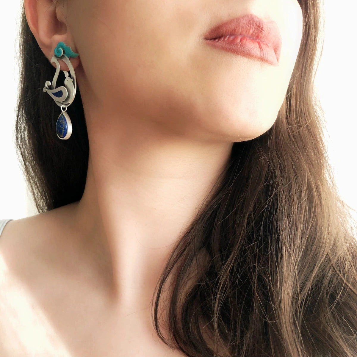 model wearing pair of paisley earrings with bird and cloud design and teardrop lapis lazuli