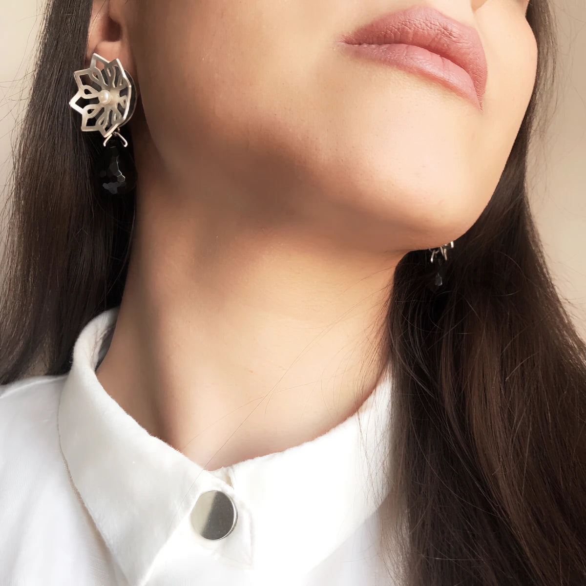 model wearing handmade silver star-shaped earrings with pearl and faceted onyx