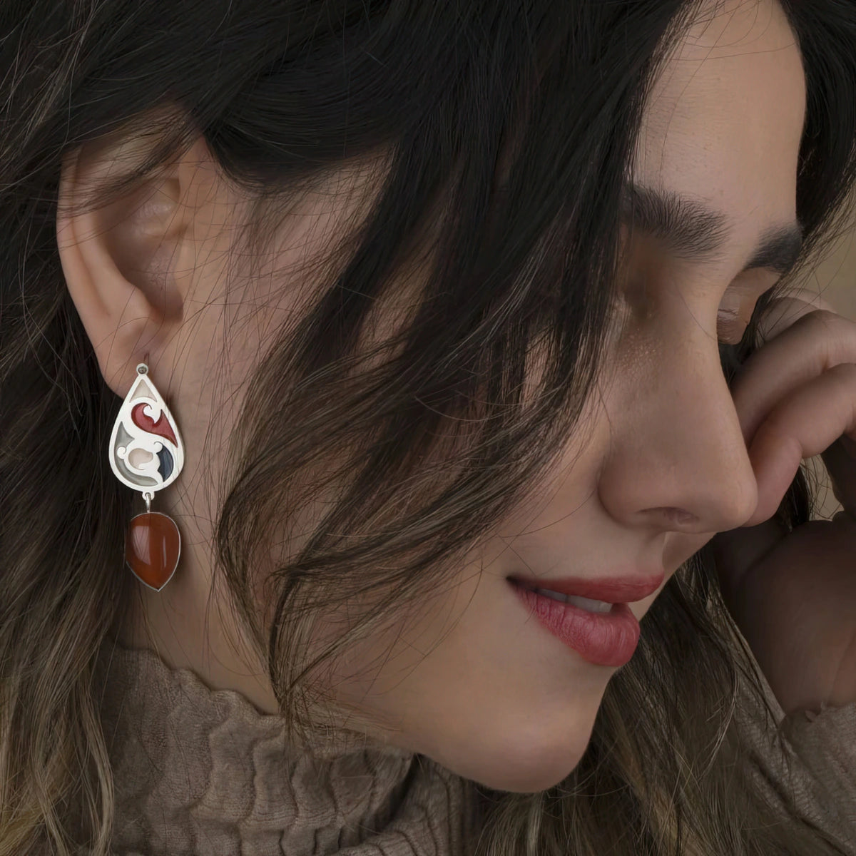 model wearings handmade silver and enamel dangle earrings decorated with red jasper