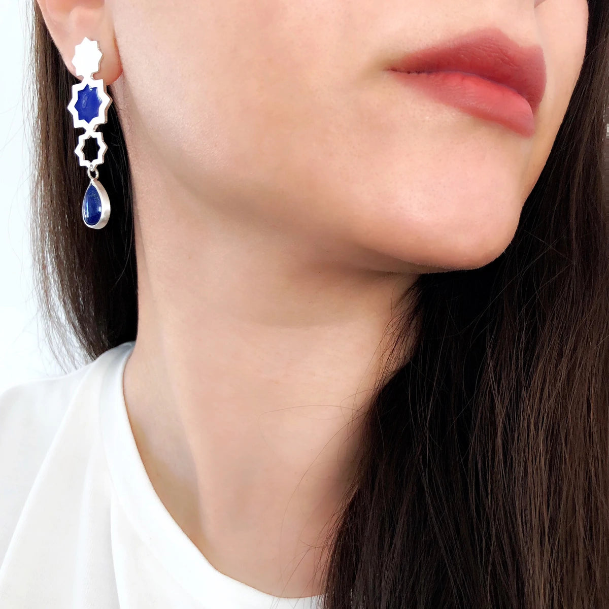model wearing handmade silver stars drop earrings with blue enamel and teardrop lapis lazuli