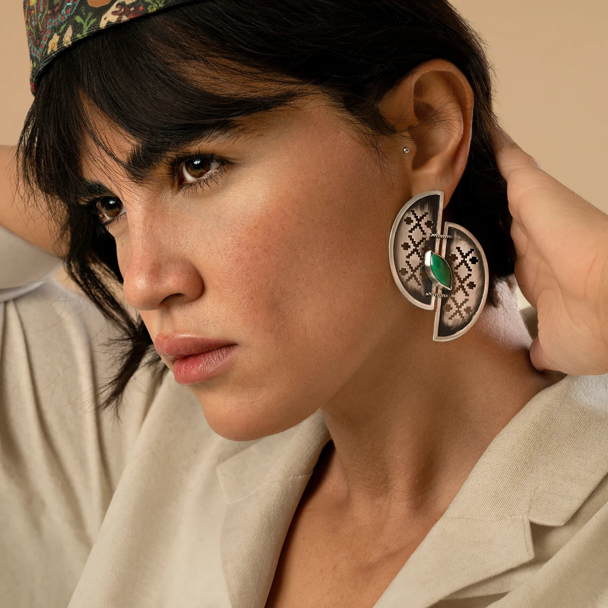 model wearing handmade openwork oxidized silver statement earrings in the shape of 2 half-circles with malachite