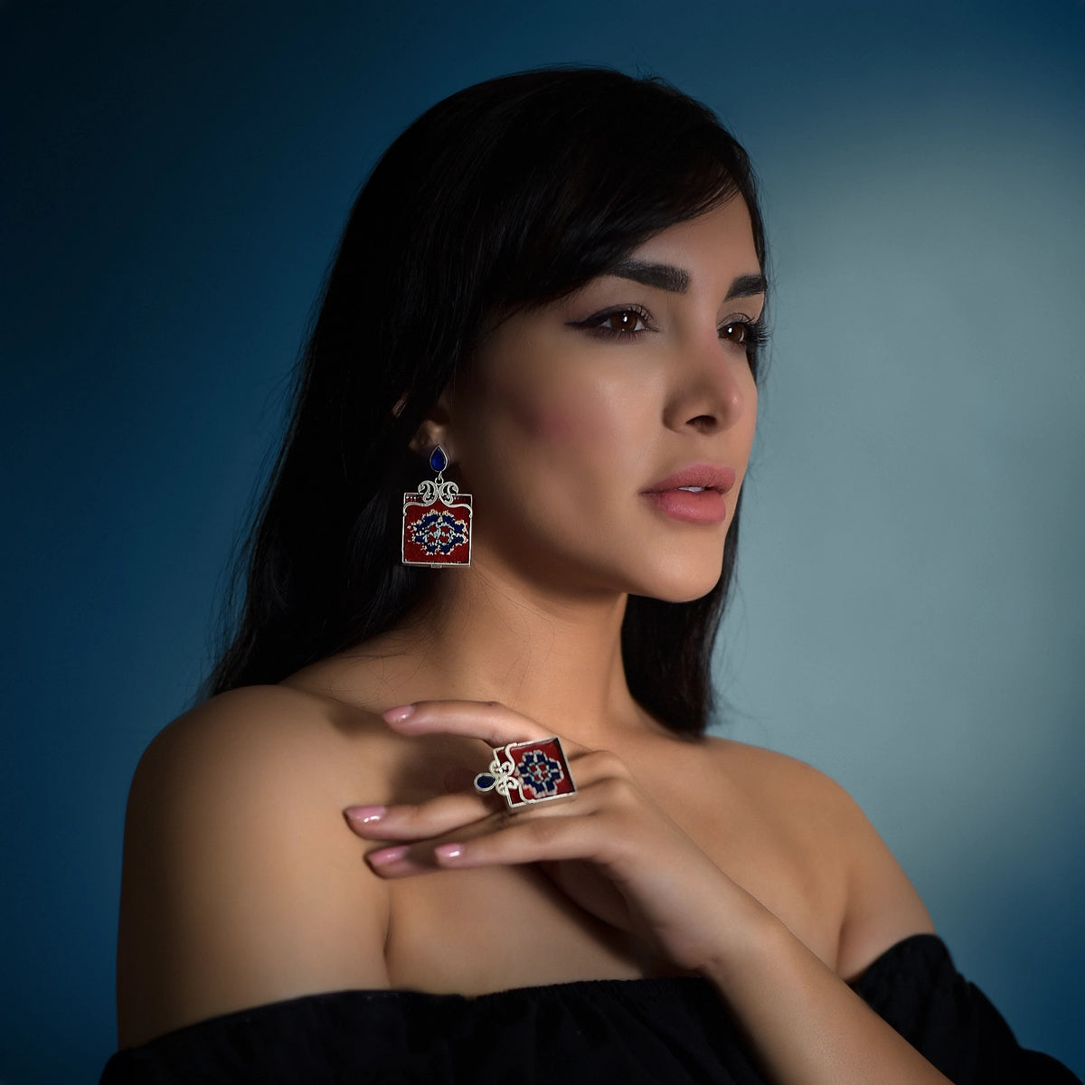 model wearing handmade silver and Persian rug statement earrings and ring with openwork paisley pattern and blue cubic zirconia