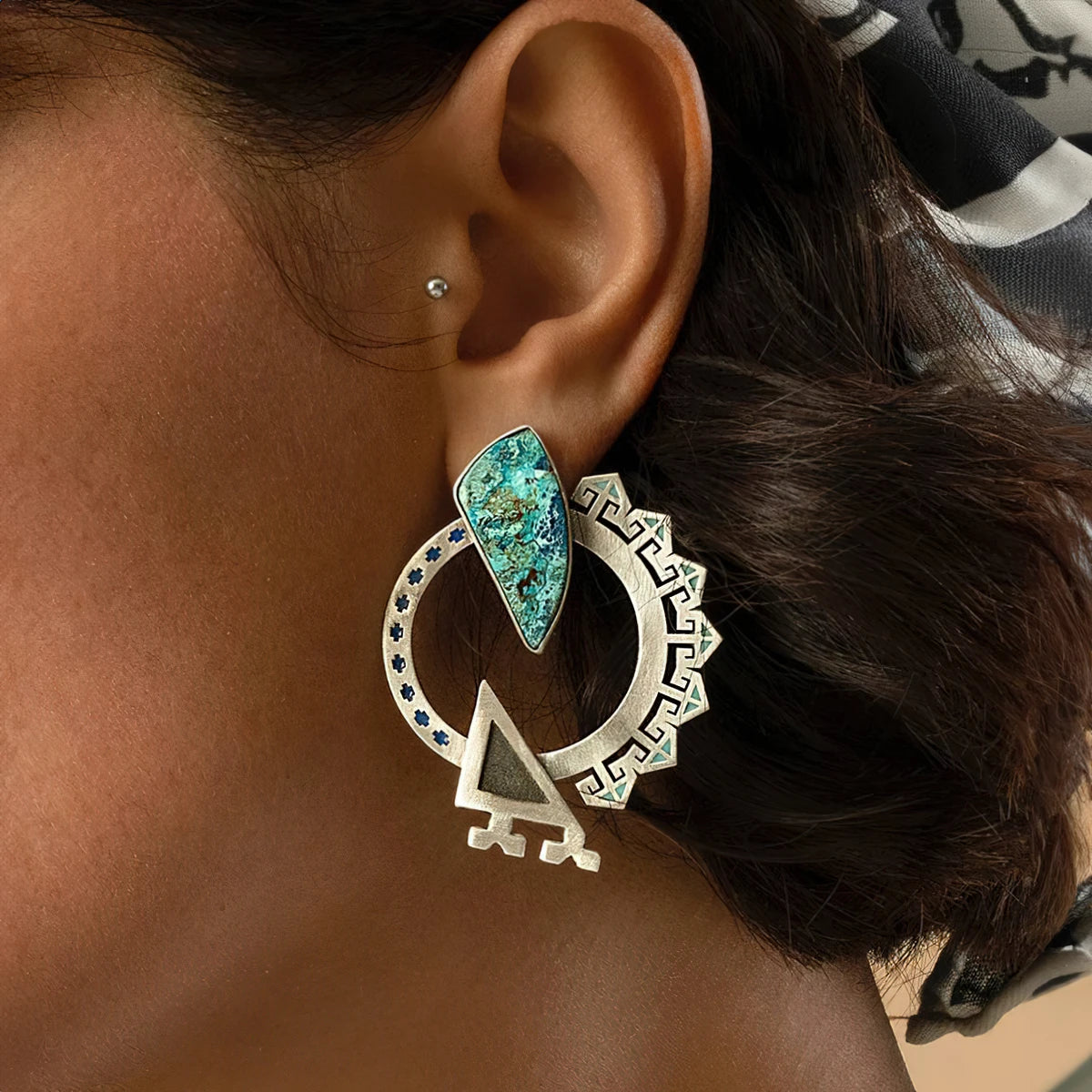 model wearing handmade silver and enamel statement earring with shattuckite and oxidized silver accents.
