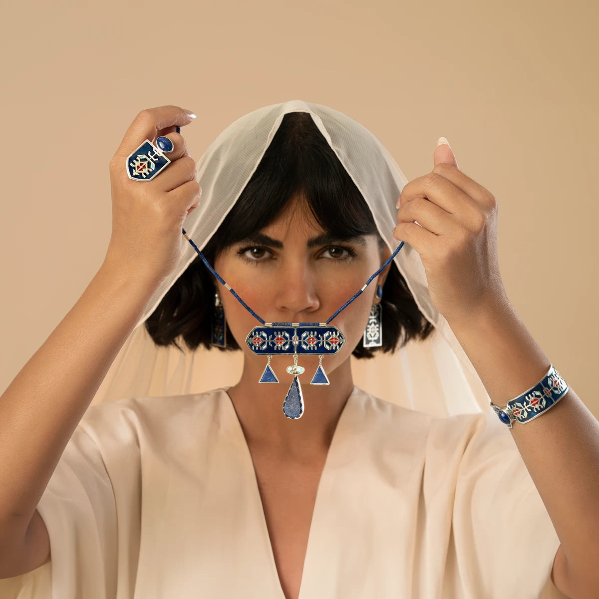 model wearing handmade statement silver jewelry set with geometric patterns and decorated with blue enamel and red accents, lapis lazuli and turquoise.