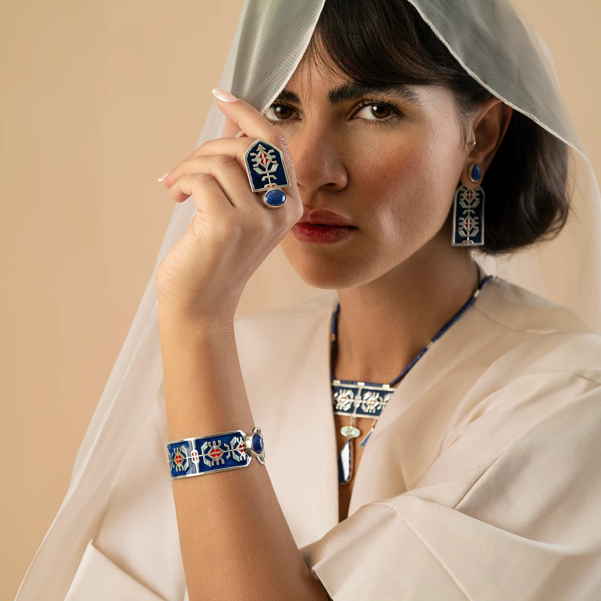 model wearing handmade statement silver jewelry set with geometric patterns and decorated with blue enamel and red accents, lapis lazuli and turquoise.