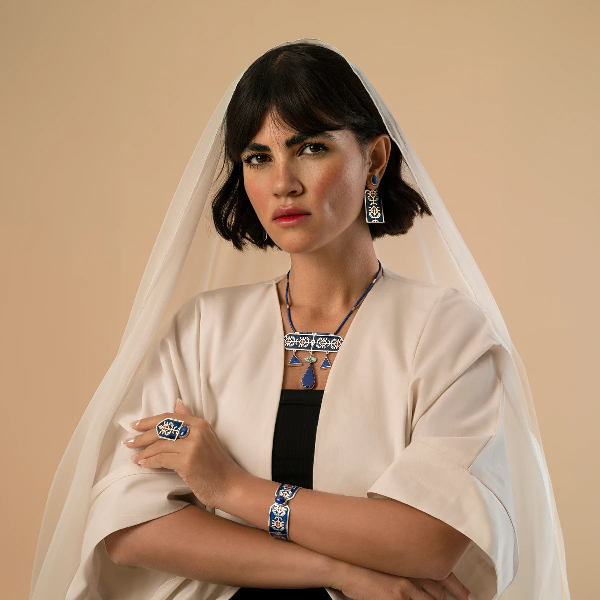 model wearing handmade statement silver jewelry set with geometric patterns and decorated with blue enamel and red accents, lapis lazuli and turquoise.