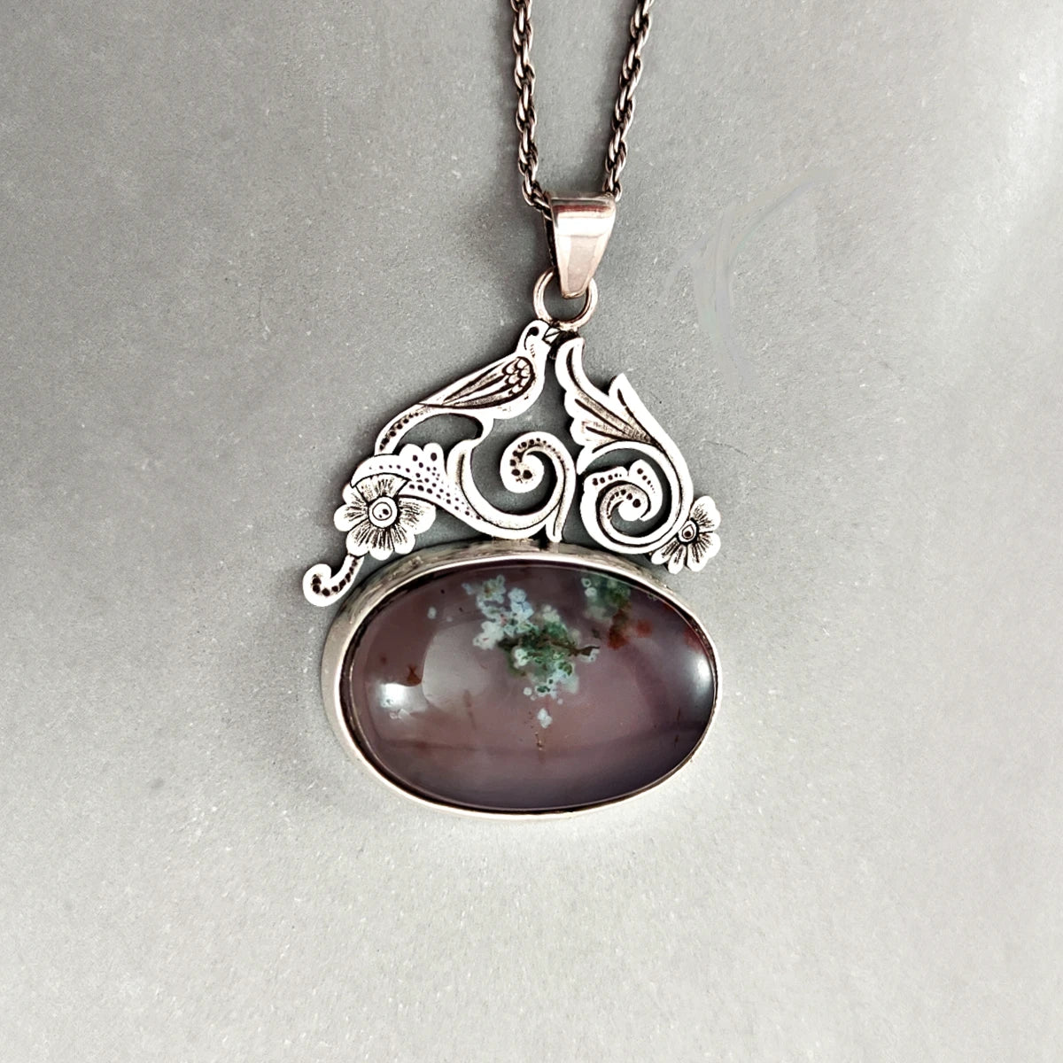 hand-engraved silver pendant with bird and floral motifs decorated with dendritic agate