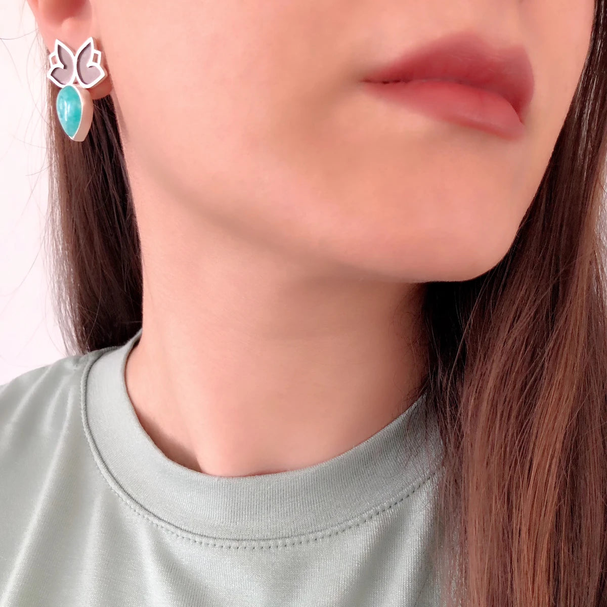 model wearing handmade mismatched stud earrings decorated with two flowers and teardrop amazonite