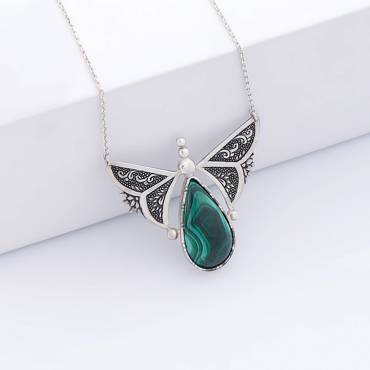 hand-engraved silver butterfly necklace with floral patterns and malachite gemstone