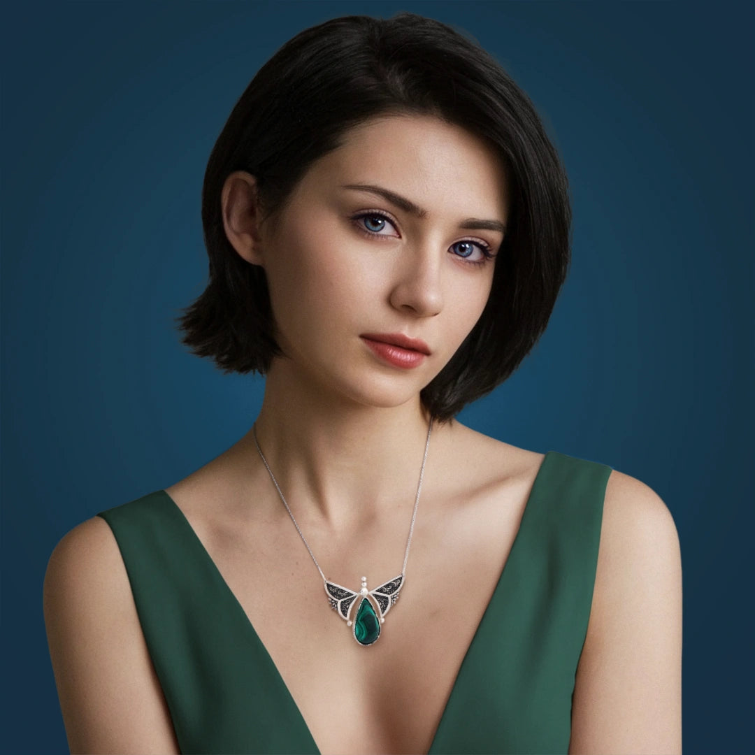 model wearing hand-engraved silver butterfly necklace with floral patterns and malachite gemstone