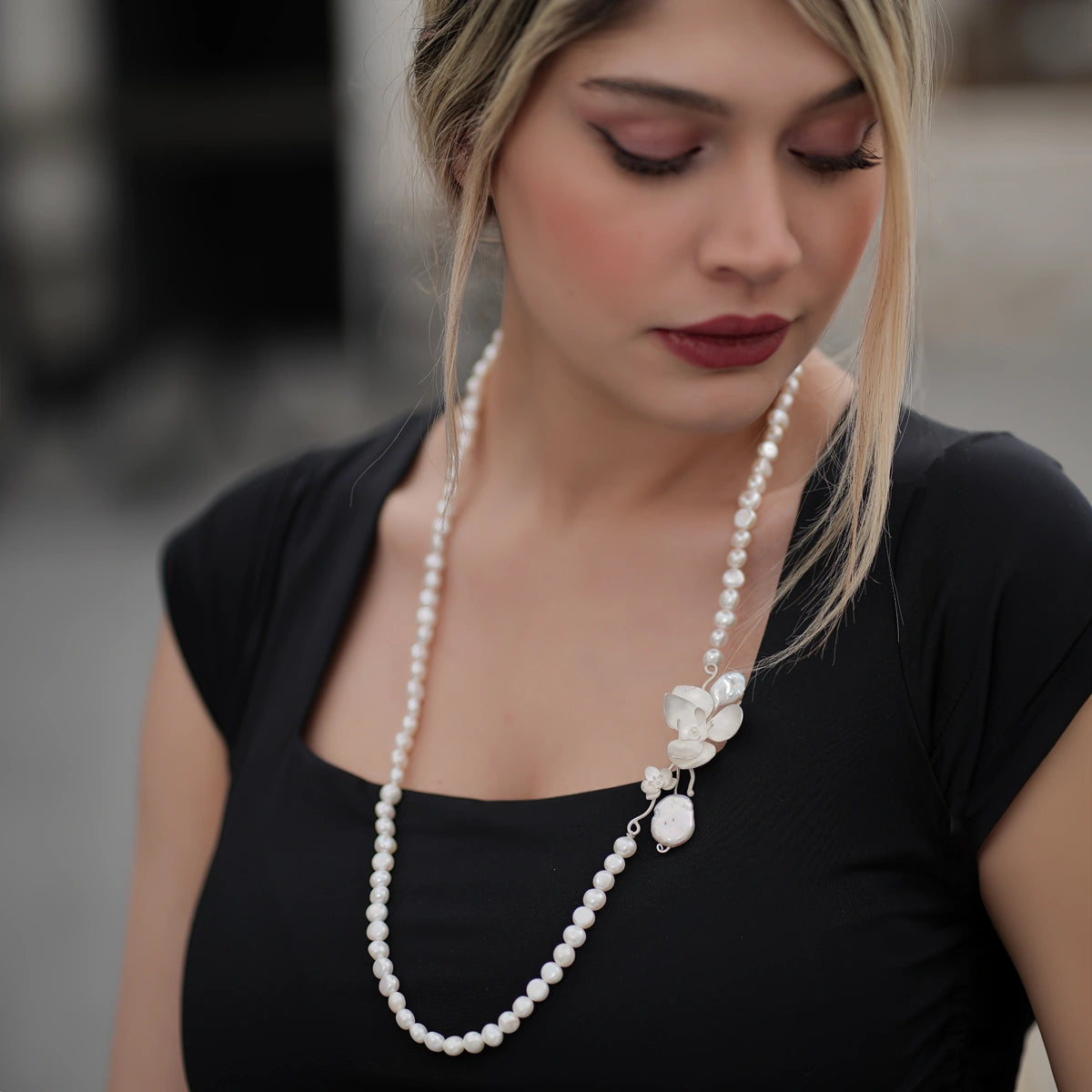 model wearing handmade silver matinee opera pearl necklace with silver orchids