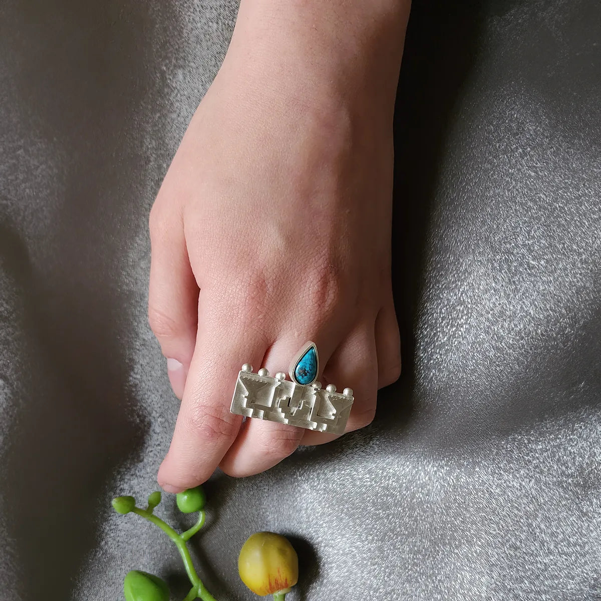 model wearing handmade silver embossed peacocks statement ring decorated with teardrop turquoise