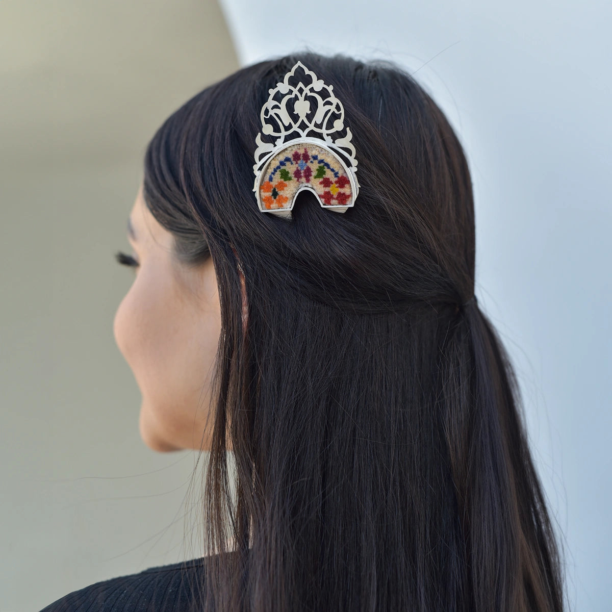 model wearing handmade silver hairpin with intricated details decorated with handwoven Persian rug