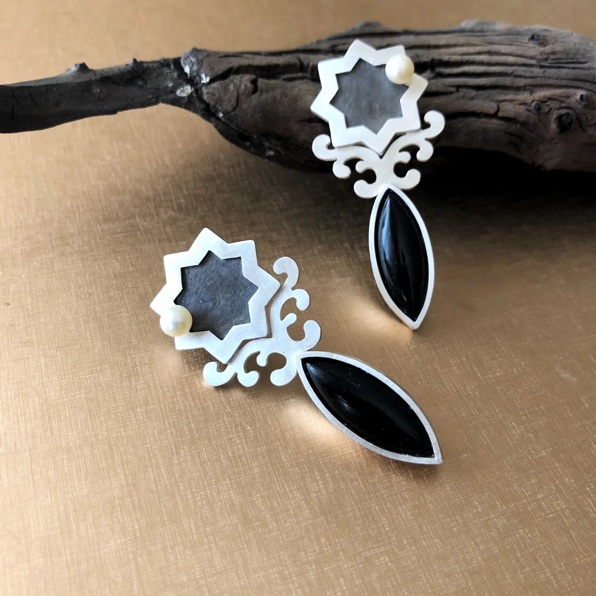 handmade silver statement earrings in the shape of star, decorated with floral patterns and an onyx gemstone
