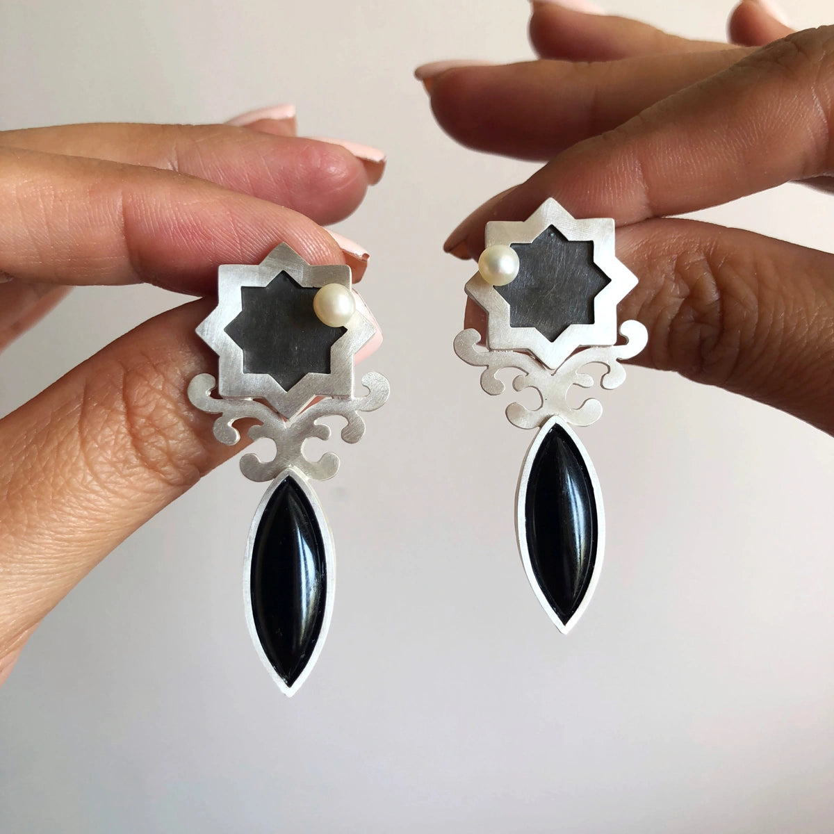 handmade silver statement earrings in the shape of star, decorated with floral patterns and an onyx gemstone