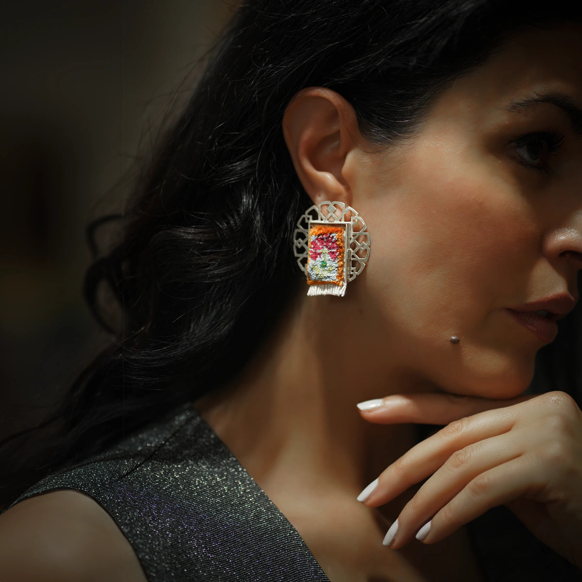 model wearing handmade openwork silver statement earrings with silk Persian rug