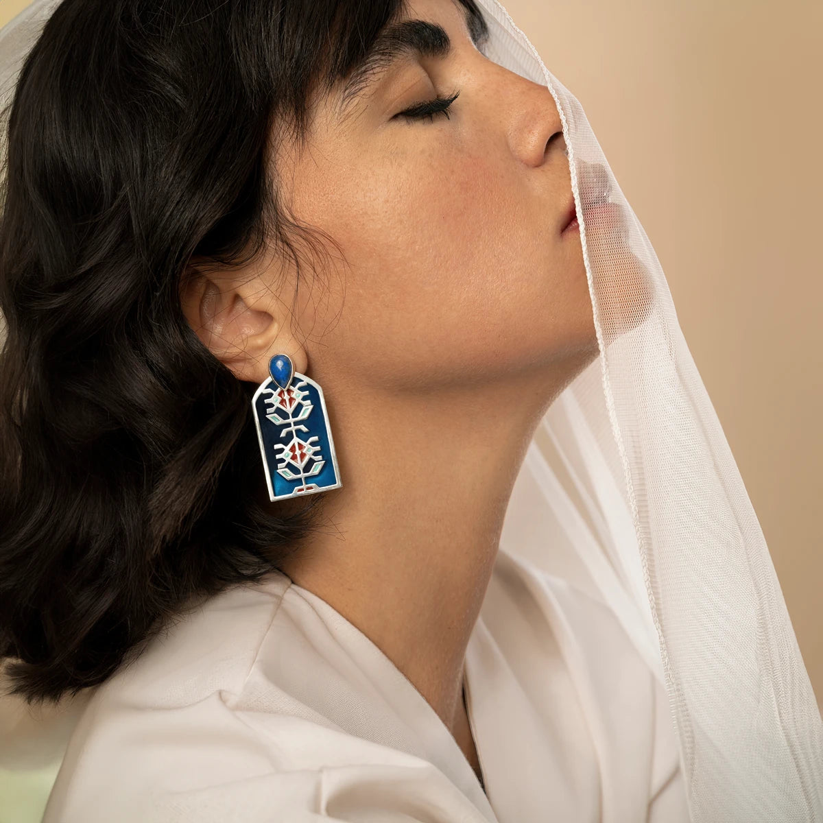 model wearing handmade silver statement earrings with geometric patterns, blue and red enamel accents and lapis lazuli