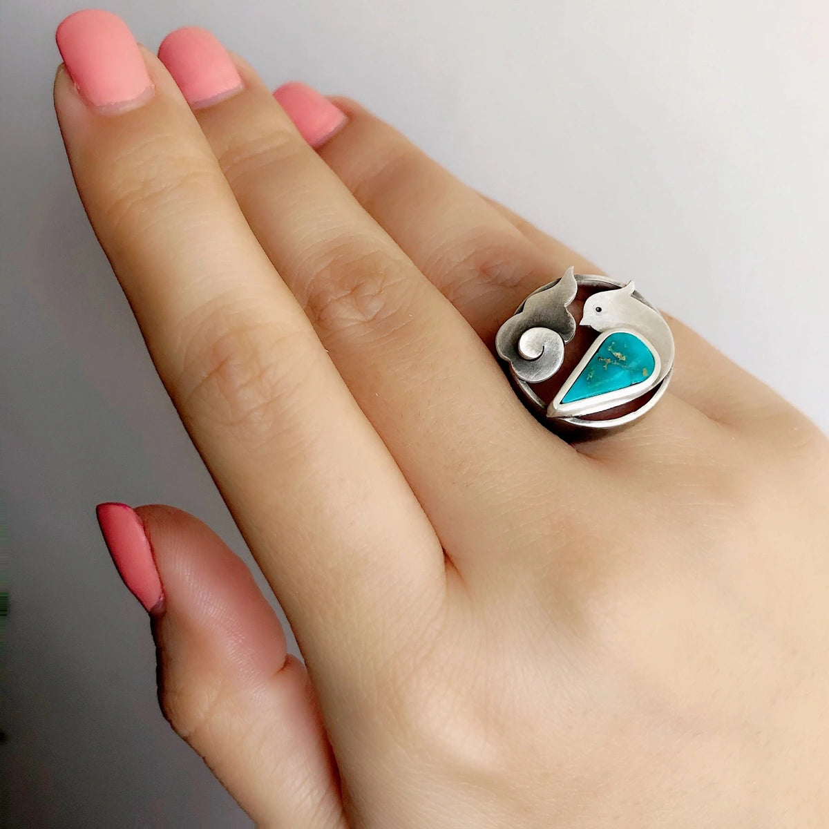 hand wearing handmade bird and cloud statement silver ring with turquoise