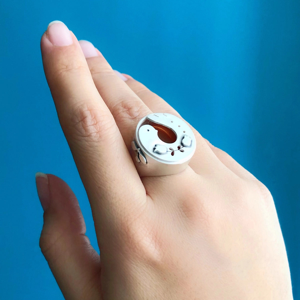 model wearing handmade silver statement bird ring with flower motifs