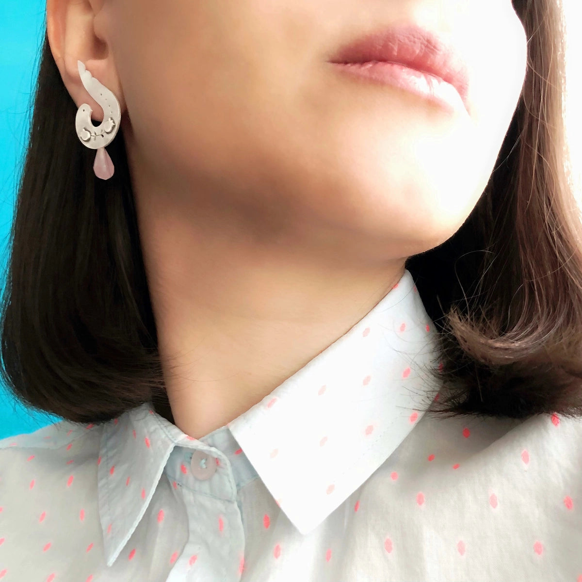 model wearing handmade silver stud earrings in the shape of a bird with rose quartz