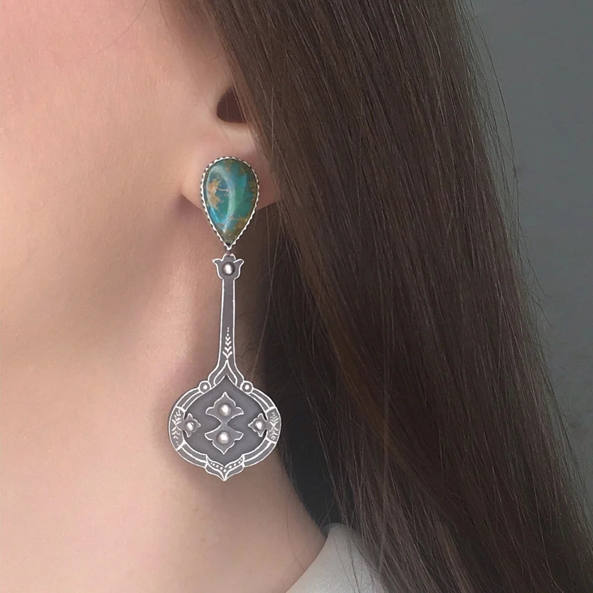 model wearing handmade oxidized silver mismatched drop earrings, adorned with turquoise