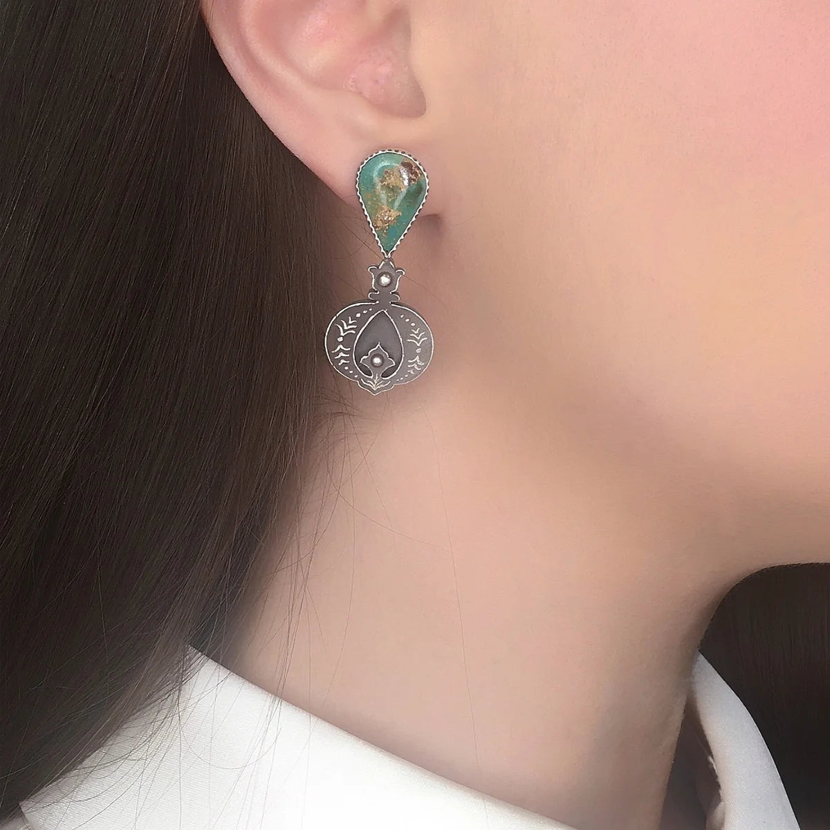 model wearing handmade oxidized silver mismatched drop earrings, adorned with turquoise