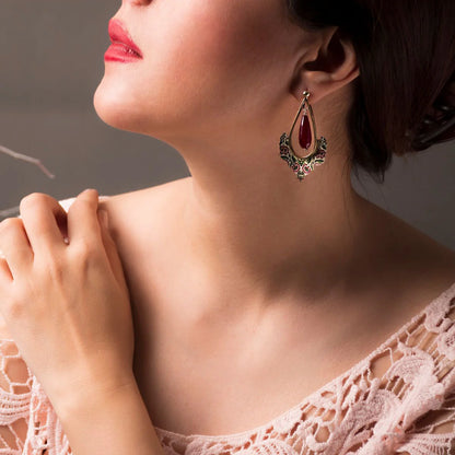 model wearing handmade statement silver earrings with ruby agate gemstones and red and green floral patterns