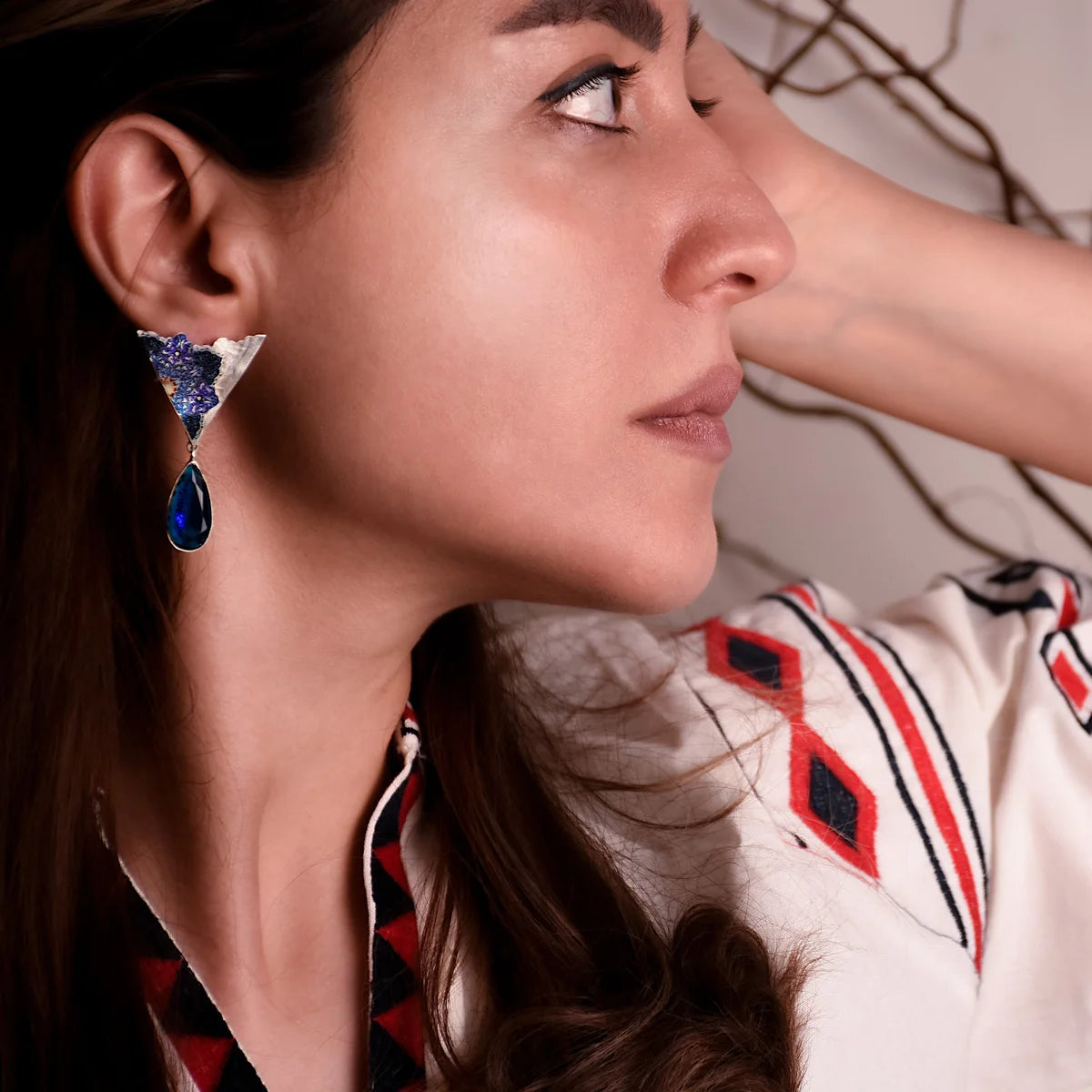 model wearing handmade silver dangle earrings with blue floral patterns and blue cubic zirconia crystals