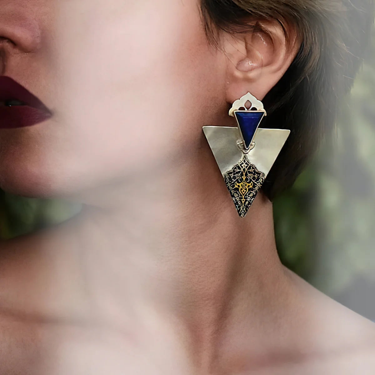 Woman wearing handmade silver statement drop earrings in rectangular shape decorated with floral patterns and rectangle lapis lazuli.