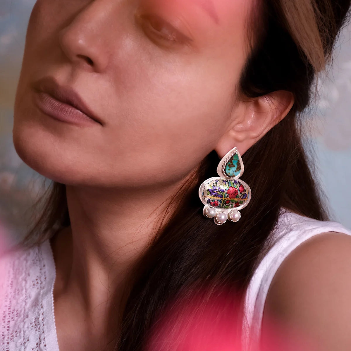 model wearing handcrafted silver statement stud earrings, decorated with multicolored floral patterns, pearls and turquoise