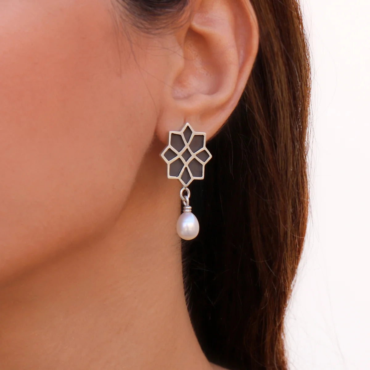 model wearing geometric star handmade silver drop earrings with pearl