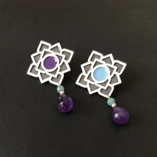 Handmade sterling silver lotus dangle earrings with oxidized silver petals, blue and violet enamel centers, aqua accent beads, and faceted purple crystal teardrops.