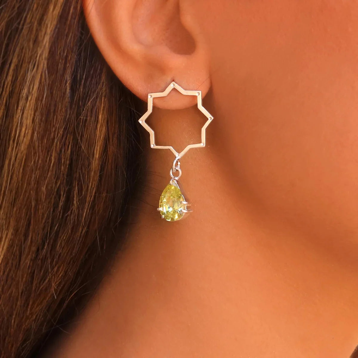 model wearing handmade silver mismatched star shaped  stud dangle earrings with yellow cubic zirconia