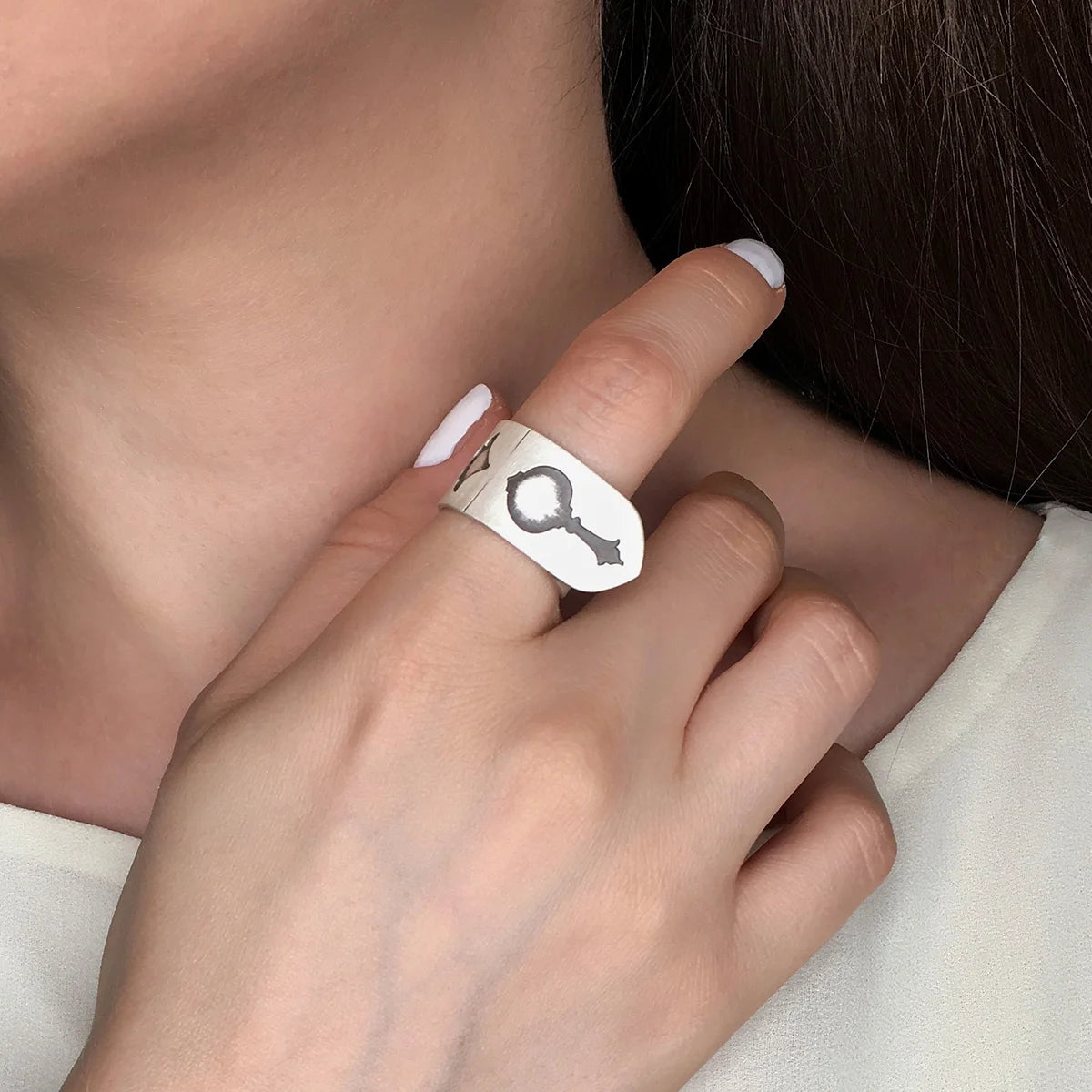 model wearing handmade oxidized silver statement ring with musical instrument shapes indented 