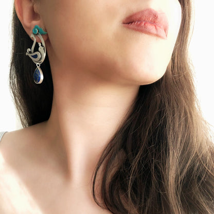 model wearing pair of paisley earrings with bird and cloud design and  teardrop lapis lazuli