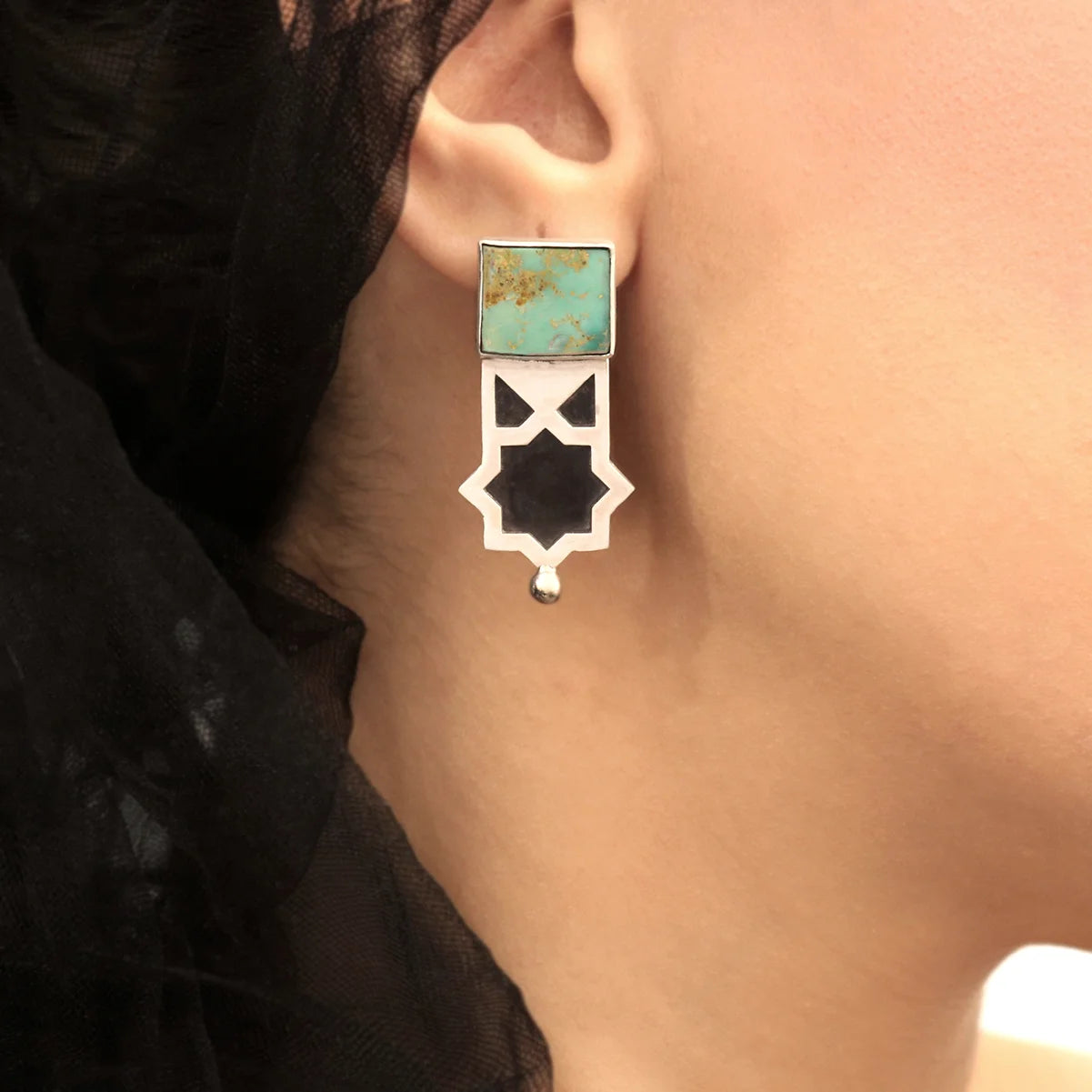 model wearing handmade silver stud drop earrings with square turquoise and geometric star