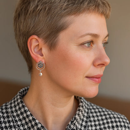 model wearing handmade mismatched silver dangle earrings with rope-textured circles, faux pearls, and oxidized floral medallion design