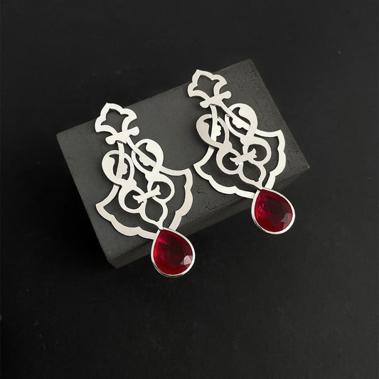 Handmade sterling silver openwork earrings with interwoven floral patterns and faceted teardrop red crystals.