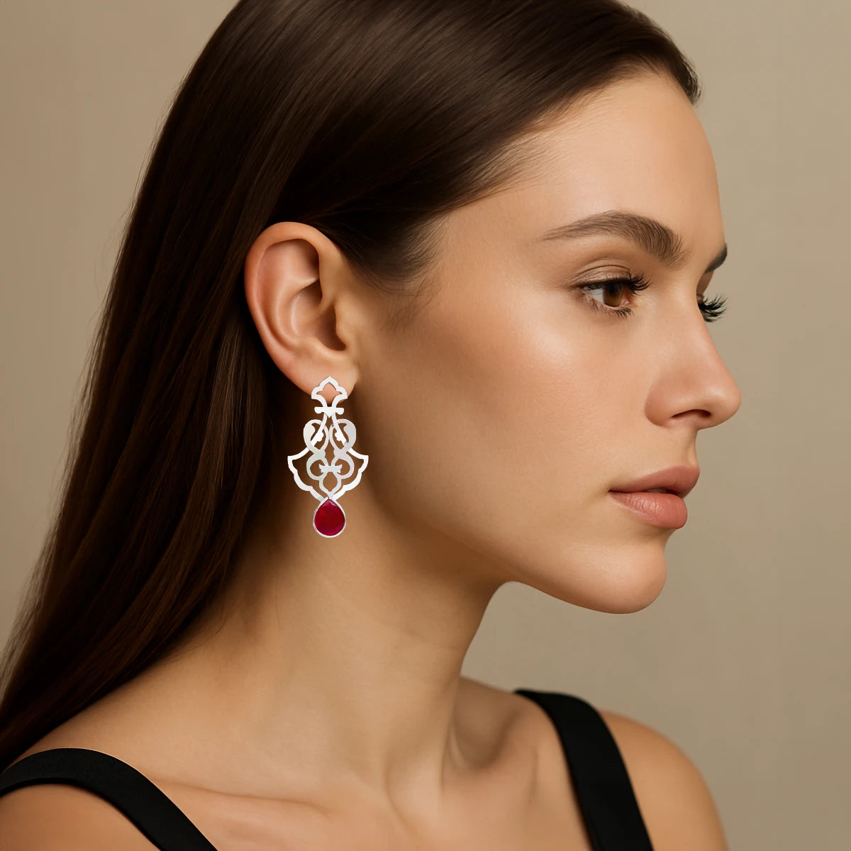 model wearing Handmade sterling silver openwork earrings with interwoven floral patterns and faceted teardrop red crystals.