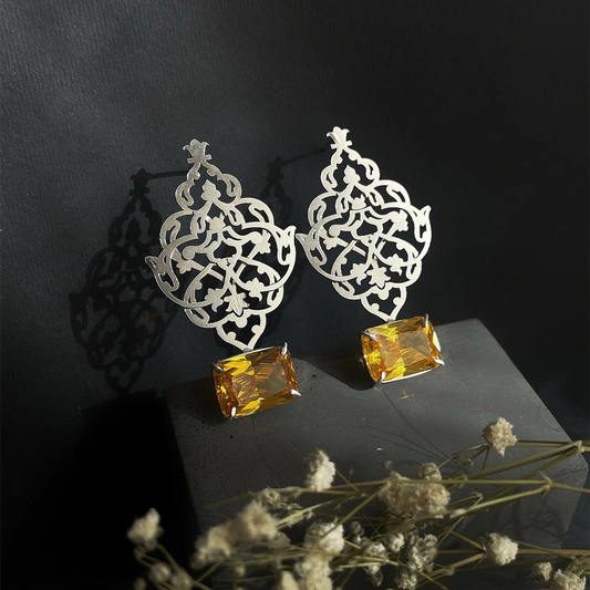 Handmade silver openwork earrings with intricate Persian-inspired floral motifs and yellow crystals.
