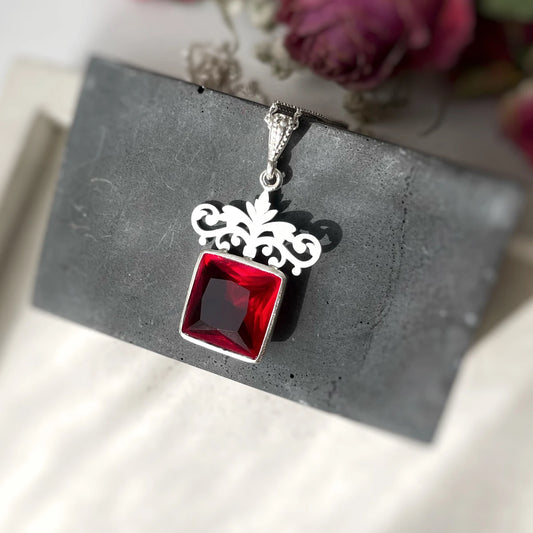 Handmade sterling silver pendant necklace with square red crystal and ornate floral crown design.