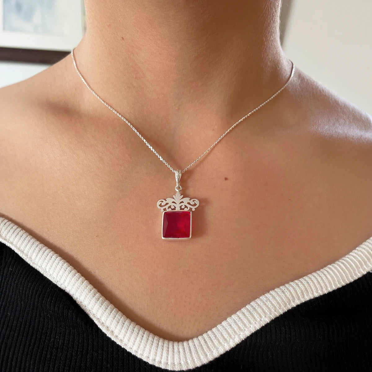 model wearing handmade sterling silver pendant necklace with square red crystal and ornate floral crown design.
