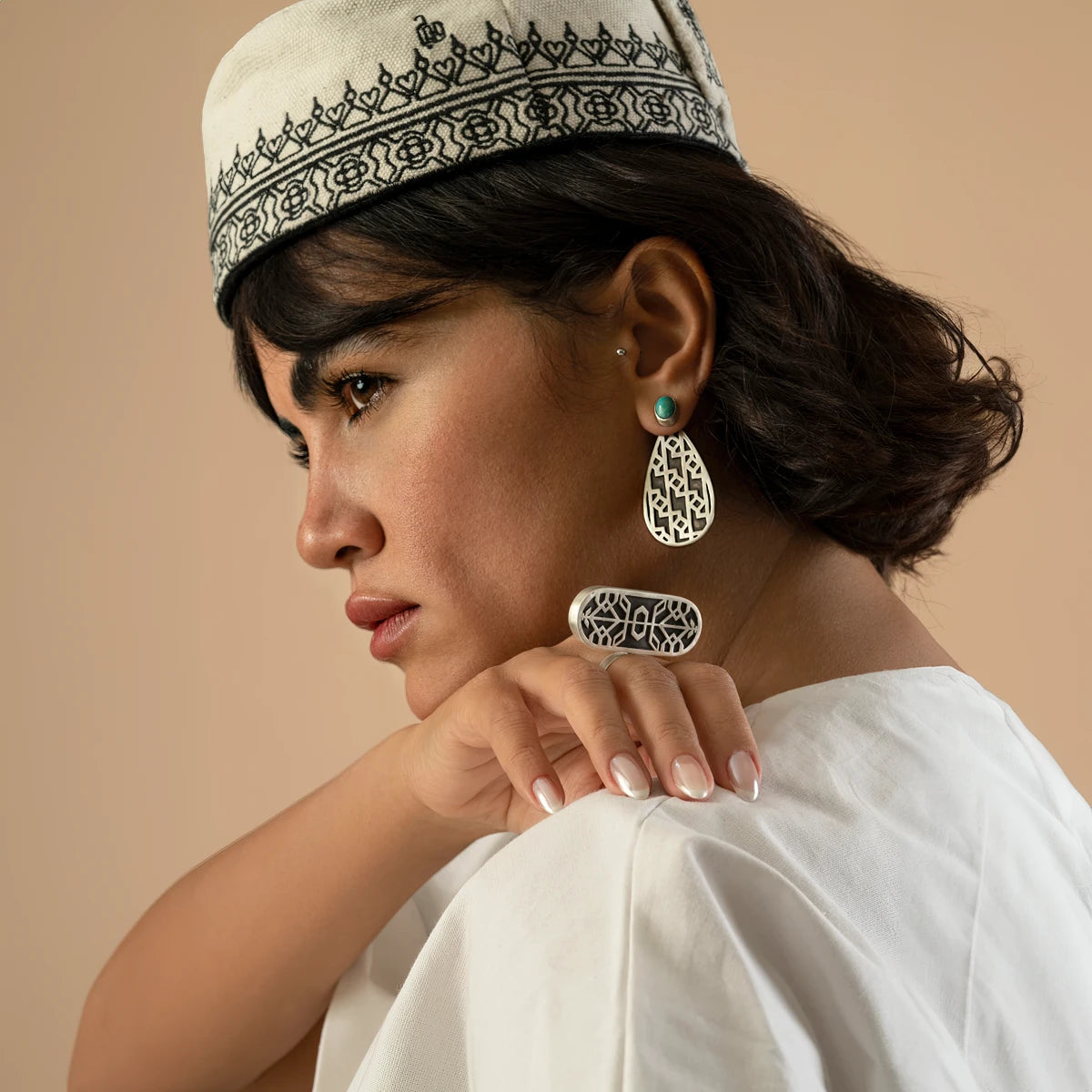 model wearing handmade silver teardrop earrings with oxidized parts and geometric patterns decorated with turquoise