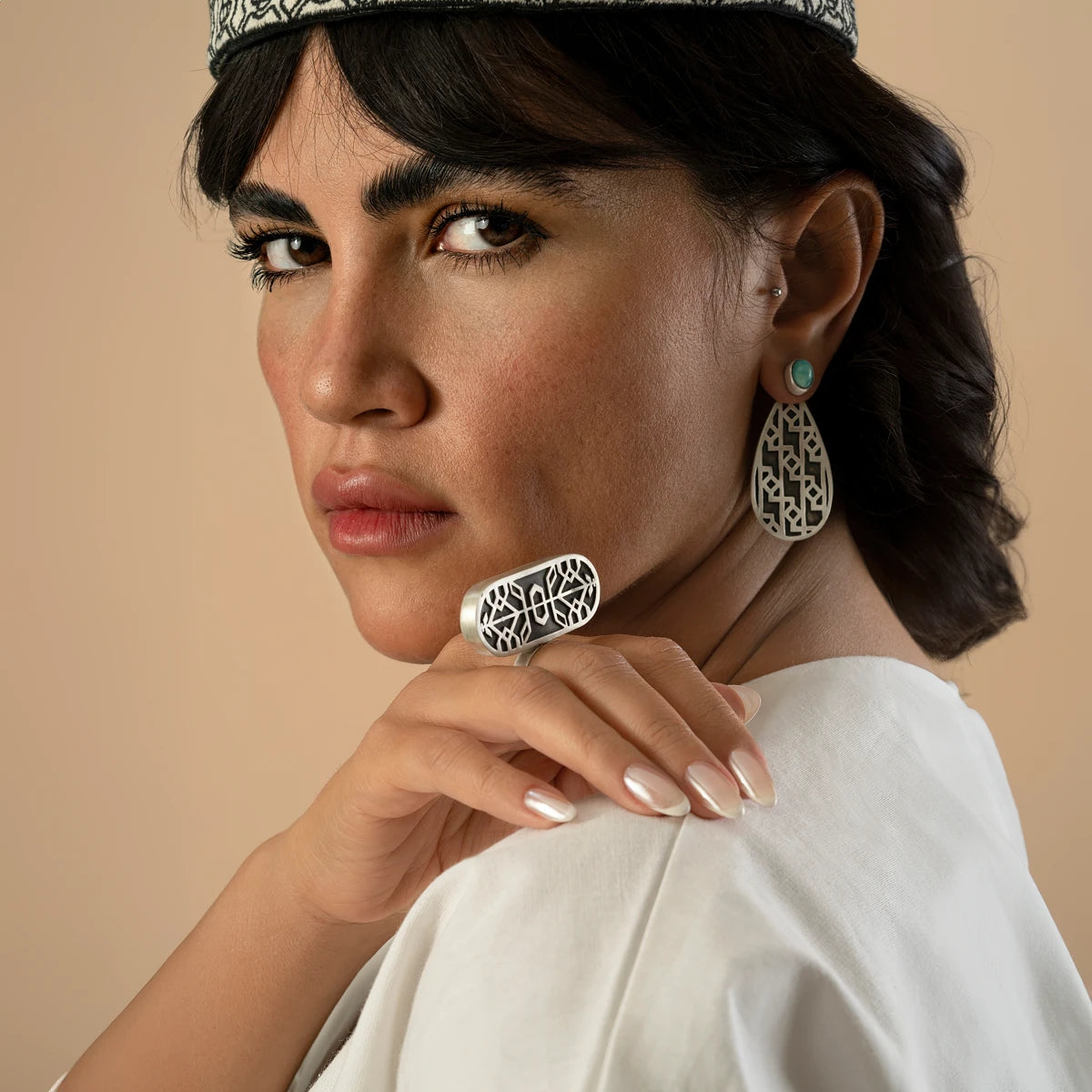 model wearing handmade silver teardrop earrings with oxidized parts and geometric patterns decorated with turquoise